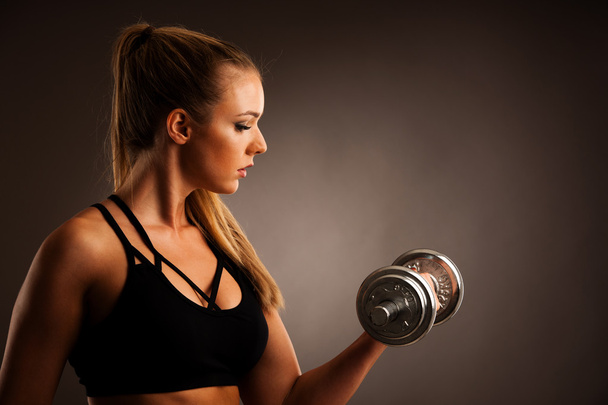 fit woman workout with dumbbells in gym studio photography of a  - Fotografie, Obrázek