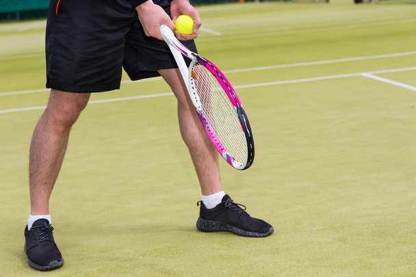 Male player's hand with tennis ball getting ready to serve on a  - Foto, Imagem