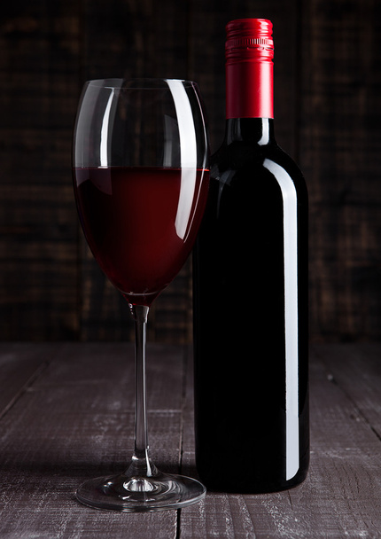 Flasche und Glas Rotwein auf Holzplatte  - Foto, Bild