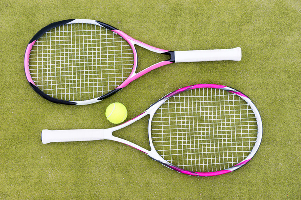 Tennis rackets with ball on green background - Foto, afbeelding
