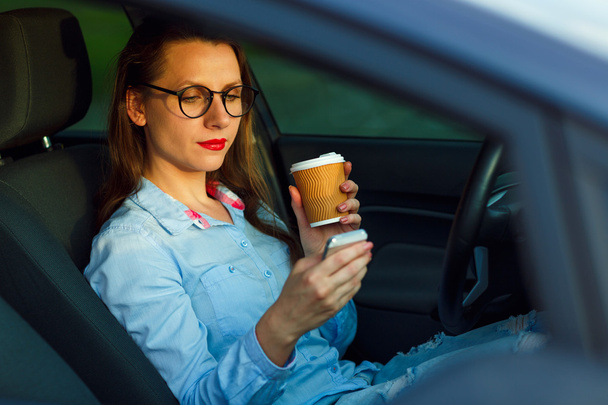 Businesswoman sending a text message and drinking coffee while d - Foto, Bild