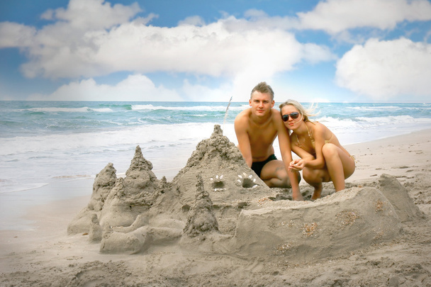 young couple near sand castle on beach - Photo, Image