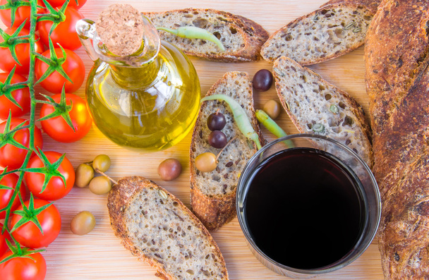 Baguette, olives, huile d'olive, verre de vigne, poivrons et tomates
. - Photo, image