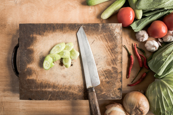 Το Top view μαχαίρι σε ξύλινος τεμαχίζοντας φραγμός με φρέσκα λαχανικά - Φωτογραφία, εικόνα
