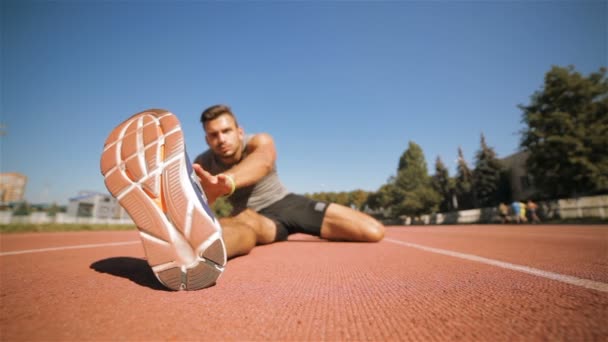 männlicher Athlet streckt sein Bein im Stadion - Filmmaterial, Video
