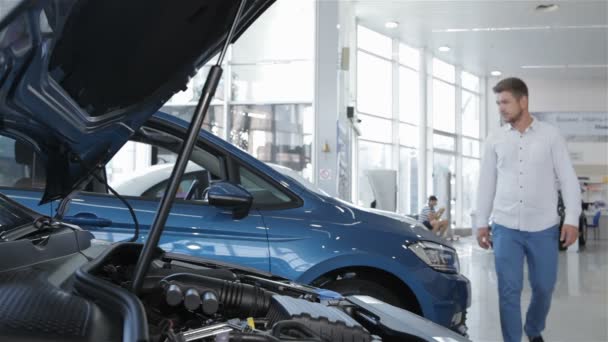 Man looks at the engine compartment of the car at the dealership - Footage, Video