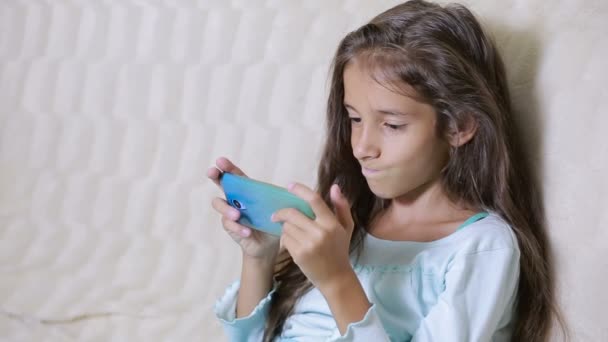 Girl child with a cell phone browses the Internet - Video