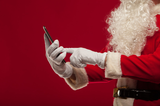 Moderne Kerstman met behulp van tablet pc op rode achtergrond. Christma - Foto, afbeelding