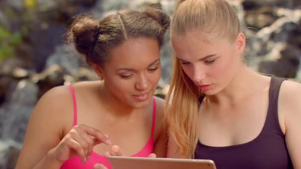 Tyttöystävät surffaavat internetissä tablet-tietokoneella ulkona
 - Materiaali, video