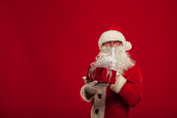 Foto de tipo Santa Claus dando regalo de Navidad y mirando a la cam
 - Foto, Imagen