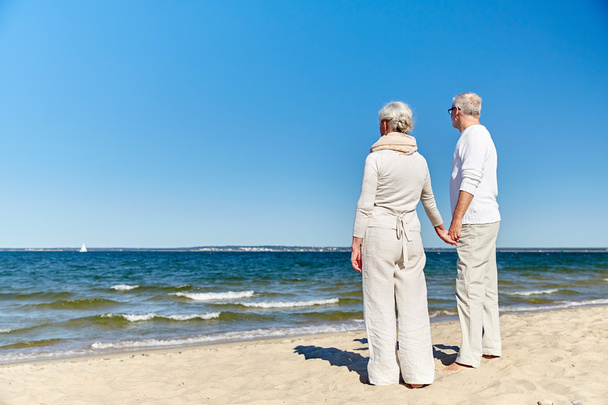 счастливая пожилая пара, держащая за руки летний пляж
 - Фото, изображение