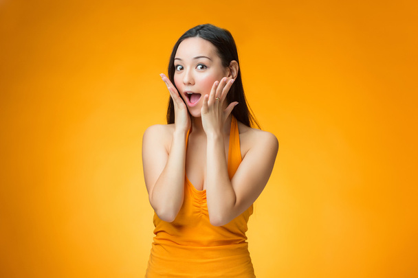 The surprised Chinese girl on yellow background - 写真・画像