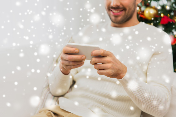 smiling man with smartphone at home for christmas - Foto, Bild