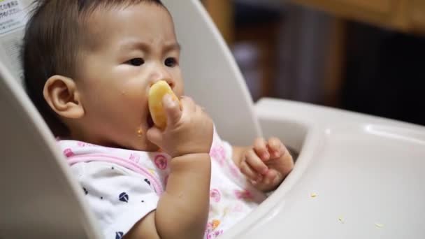 Ασίας μωρό τρώει τα τρόφιμα από τον εαυτό του - Πλάνα, βίντεο