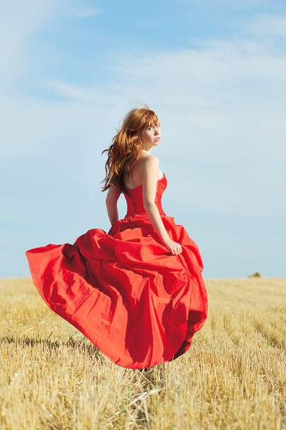 Correr novia en vestido de novia rojo en un campo
 - Foto, Imagen