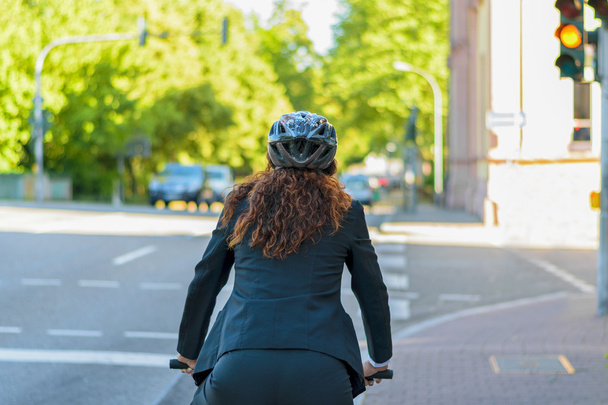 Woman cycling to work in a city - 写真・画像