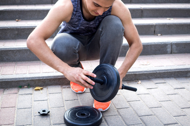 Молодий чоловік готує тупики для тренувань з вагами
 - Фото, зображення