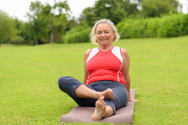 Sorridente donna anziana seduta su tappetino yoga
 - Foto, immagini