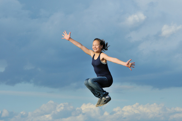Menina bonita no salto ginástica contra o céu azul
 - Foto, Imagem