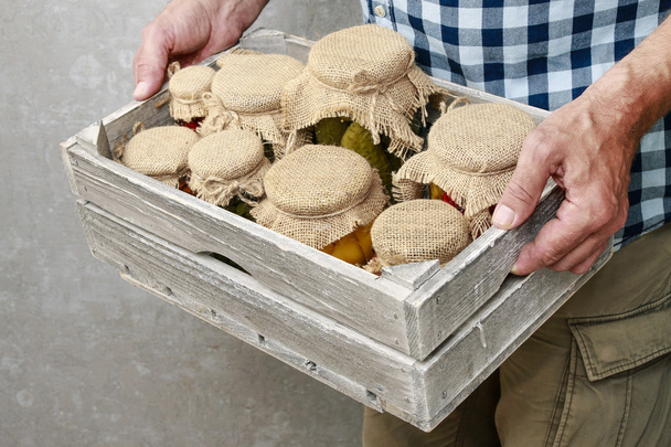 Man holding box with jars of preserves. - Zdjęcie, obraz