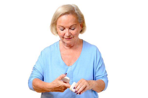 Elderly woman taking cosmetic cream from a jar - Photo, Image