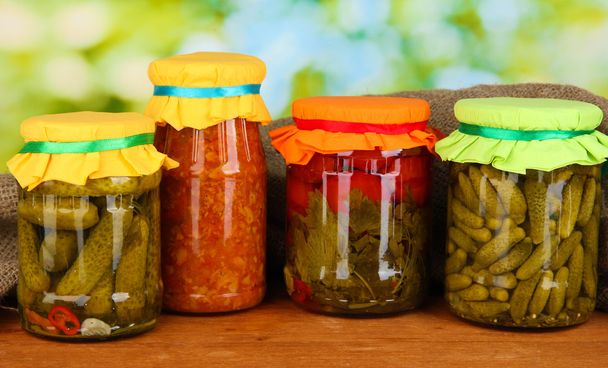 Jars with canned vegetables on green background close-up - Фото, изображение