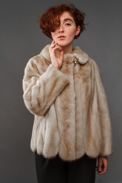 Lány téli kabát szőrme felett szürke háttér - Fotó, kép