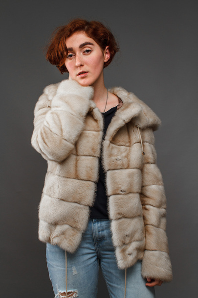Girl in winter fur coat over gray background - Photo, image