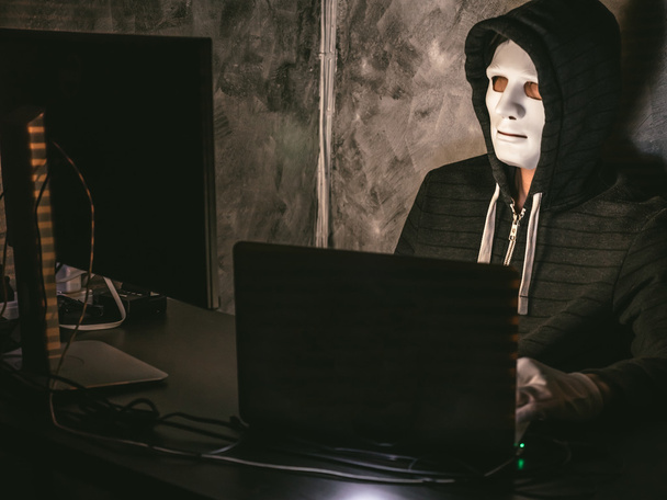 Počítačový hacker - muž v košili s kapucí s maskou krádeže dat z notebooku - Fotografie, Obrázek