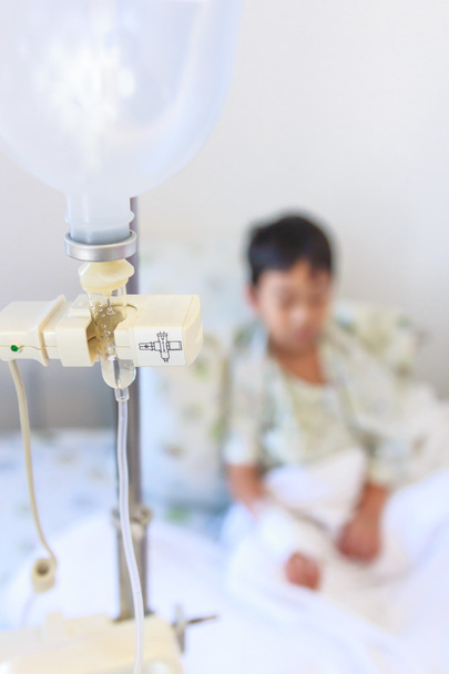 Asiático chico sentado en enfermo cama con infusión bomba intravenosa IV goteo
 - Foto, imagen