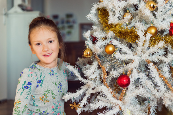 Крупный план портрета милой маленькой девочки, играющей с рождественскими игрушками
 - Фото, изображение