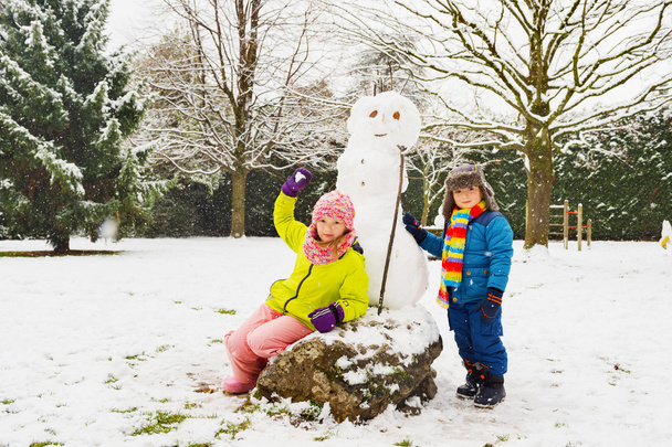 Двоє чарівних дітей грають разом у сніжному парку, одягнені в теплий зимовий одяг
 - Фото, зображення