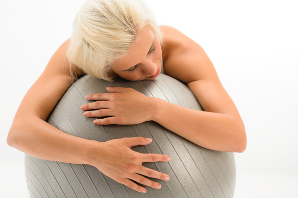 Tired sportive woman resting on fitness ball - Foto, afbeelding
