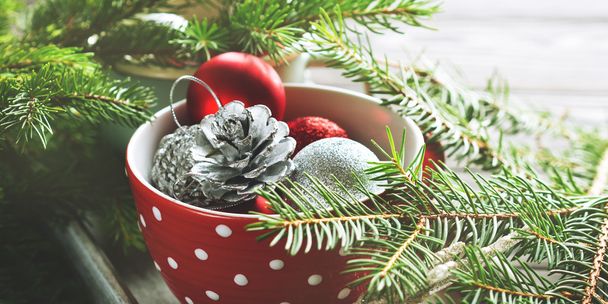 Bola de Navidad en una taza con ramas verdes
 - Foto, Imagen