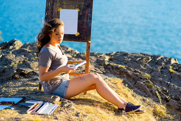 young artist draws a seascape at sunset - Foto, Imagen
