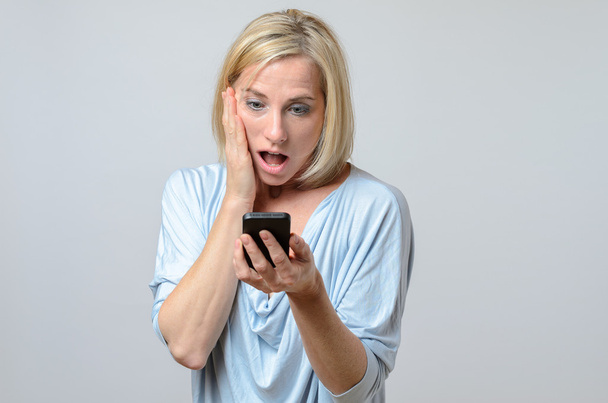 Überraschte Frau schaut auf ihr Handy - Foto, Bild
