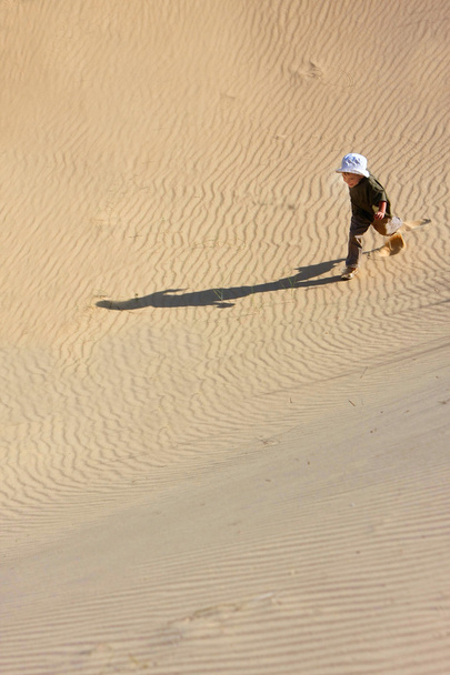 砂の砂漠で実行している若い男の子 - 写真・画像