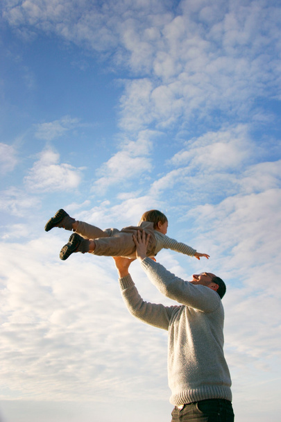 vader en zoon spelen op hemelachtergrond - Foto, afbeelding