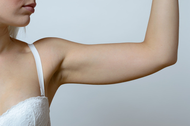 Giovane donna bionda mostrando braccio flaccido
 - Foto, immagini