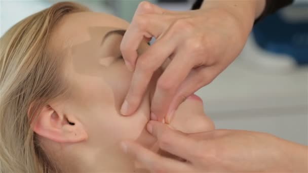 Masseur massages clients face from chin till ear - Πλάνα, βίντεο