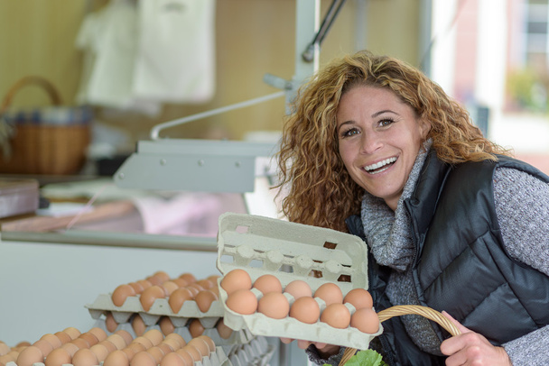 Aantrekkelijke jonge vrouw winkelen voor verse eieren - Foto, afbeelding
