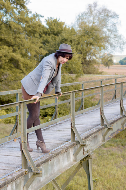Giovane donna alla moda su un ponte pedonale rustico
 - Foto, immagini