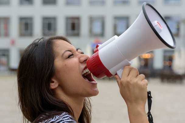 Woman yelling into a bullhorn on an urban street - Fotografie, Obrázek
