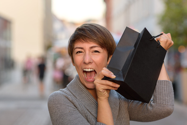 Excited woman holding up a boutique bag - Photo, Image