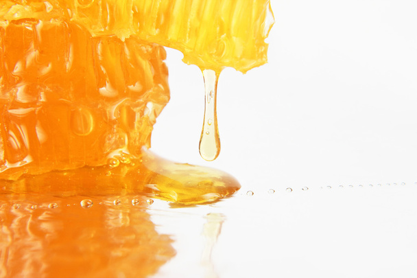 honey flowing from the honeycombs on a light background - Zdjęcie, obraz