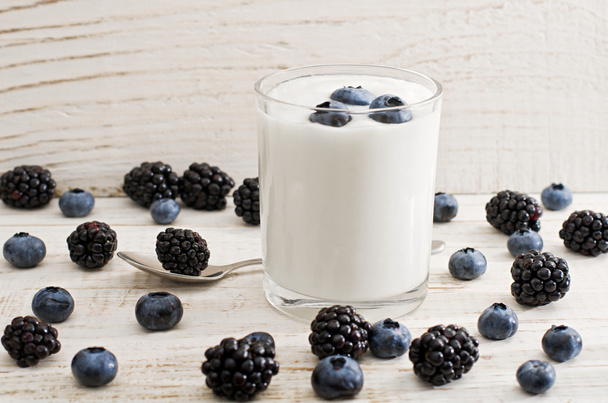 Szklanka jogurtu z borówki, jeżyny i borówki na białym tle drewnianych - Zdjęcie, obraz