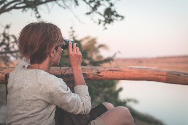 Touristen beobachten Wildtiere mit dem Fernglas auf Chobe River, namibia botswana Grenze, Afrika. Chobe Nationalpark, berühmtes Wildlife Reservat und gehobenes Reiseziel. Getöntes Image. - Foto, Bild