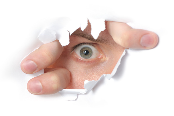 Eye looking through a hole in paper - Φωτογραφία, εικόνα