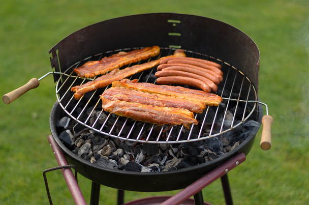 Grilling spicy sausages over a barbecue - Photo, Image