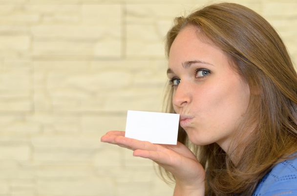 Bonita joven besando una tarjeta en blanco en la mano
 - Foto, Imagen